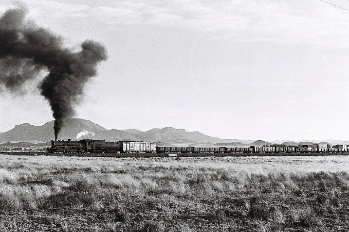 Icy cold winds sweep across the countryside and raise the smoke of the class 24 number 3700 as she heads towards Loots Berg pass. 1970's