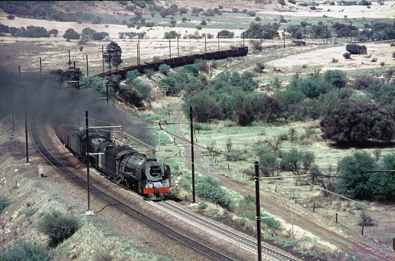 hese 2, 4-8-2s are of the 15F/23 contingent of 391 very similar locos that held "carte blanche" on the very busy Kroonstad-Bloemfontein line that was being electrified in 1974. This line was the busiest steam line in the world in 1974 with 140 trains per day, many double headed. The 23s had longer tenders, but Bloemfontein and Kroonstad locos would swap tenders between both classes so a 23F? or a 15?!! Photo: Karee, October 1974.