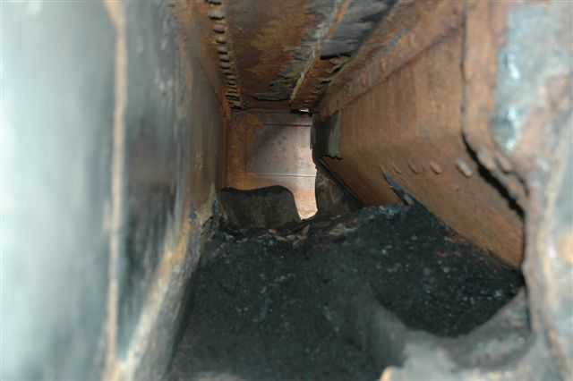 The side tunnel area of the mechanical stoker drive shaft, seen filled with coal. Upon clearing this out it revealed two large holes. This resulted in new metal panels being made to close up. <br /><br />Jan 2007