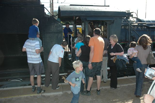 Fascinated passengers use the short stop period at Pretoria North to come examine the locomotive. Questions from: "How much coal do you use?", "Wherenis the steering wheel!", "How far do you travel on the coal?", to "Whats your name, Stoker!" are the order of the day. To get them back on board needs quite a bit of coaxing. Long Live Steam Travel!!