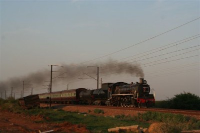 The late-running train clips along near the Carousel, past the scene of one of the numerous crash sites on this line-witness the ore truck stranded and wheel-less. C Janisch